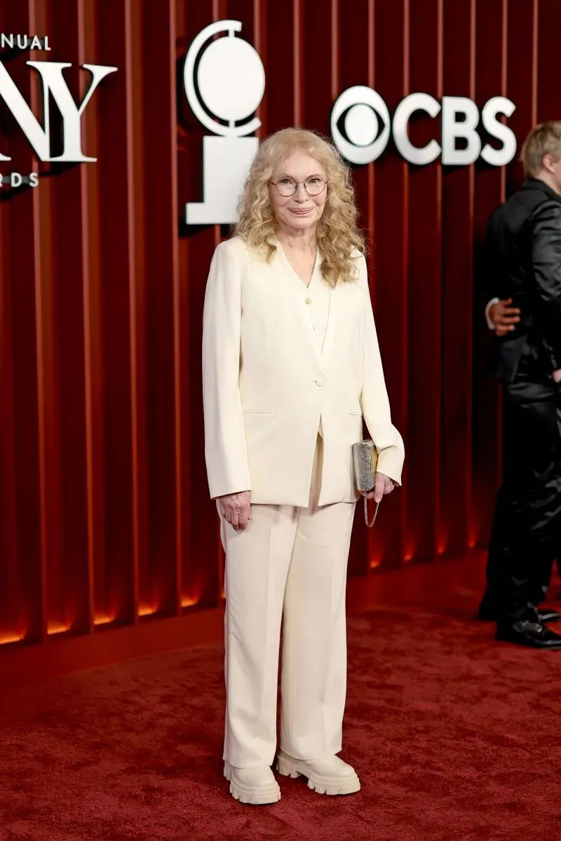 ظهور شخصية مشهورة ترتدي بدلة بيضاء أنيقة مع نظارات، على السجادة الحمراء لحفل توزيع جوائز توني في نيويورك.