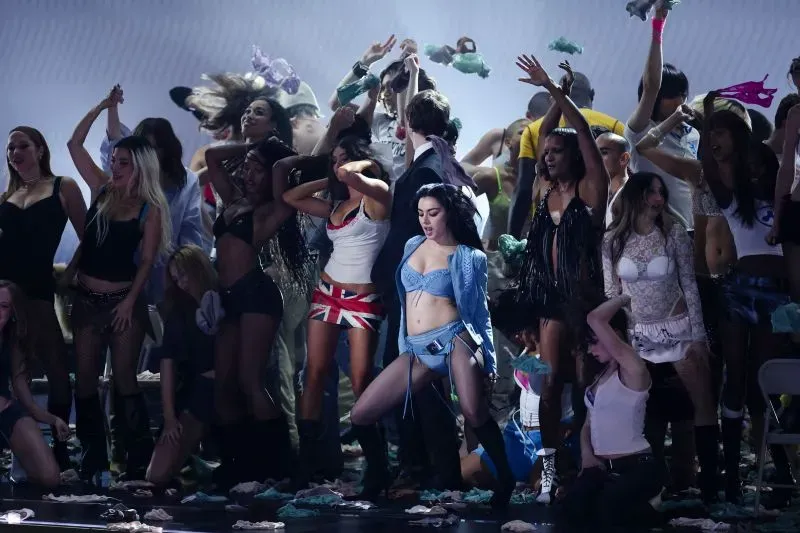 عرض حفل توزيع جوائز الموسيقى الأمريكية، حيث تتوسط مغنية ترتدي ملابس جريئة مجموعة من الراقصين في أجواء احتفالية.