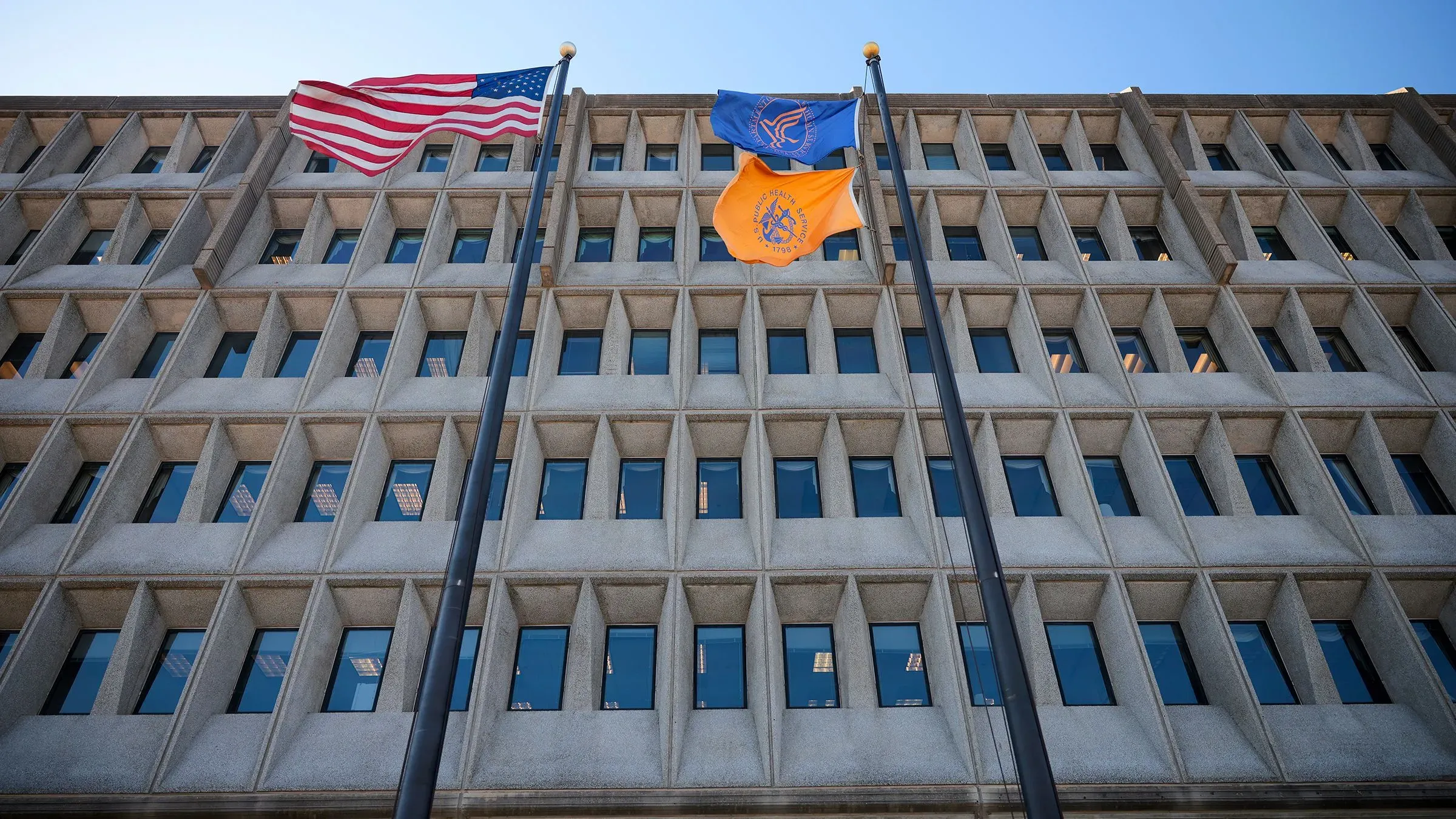 مبنى وزارة الصحة والخدمات الإنسانية في الولايات المتحدة، مع العلم الأمريكي وأعلام أخرى ترفرف أمامه، يرمز إلى قضايا الخصوصية الصحية.