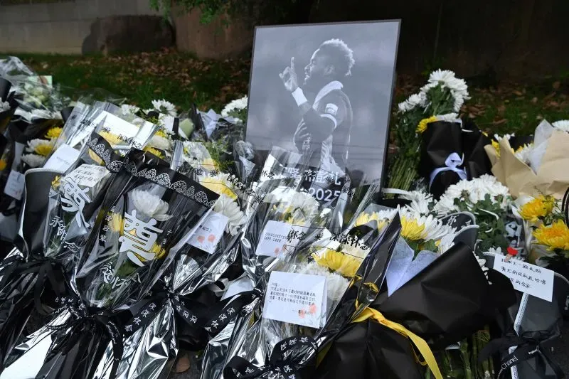 تظهر الصورة باقات من الزهور البيضاء والصفراء محاطة بصورة آرون بوبندزا، تكريمًا له بعد وفاته المأساوية عن عمر 28 عامًا.