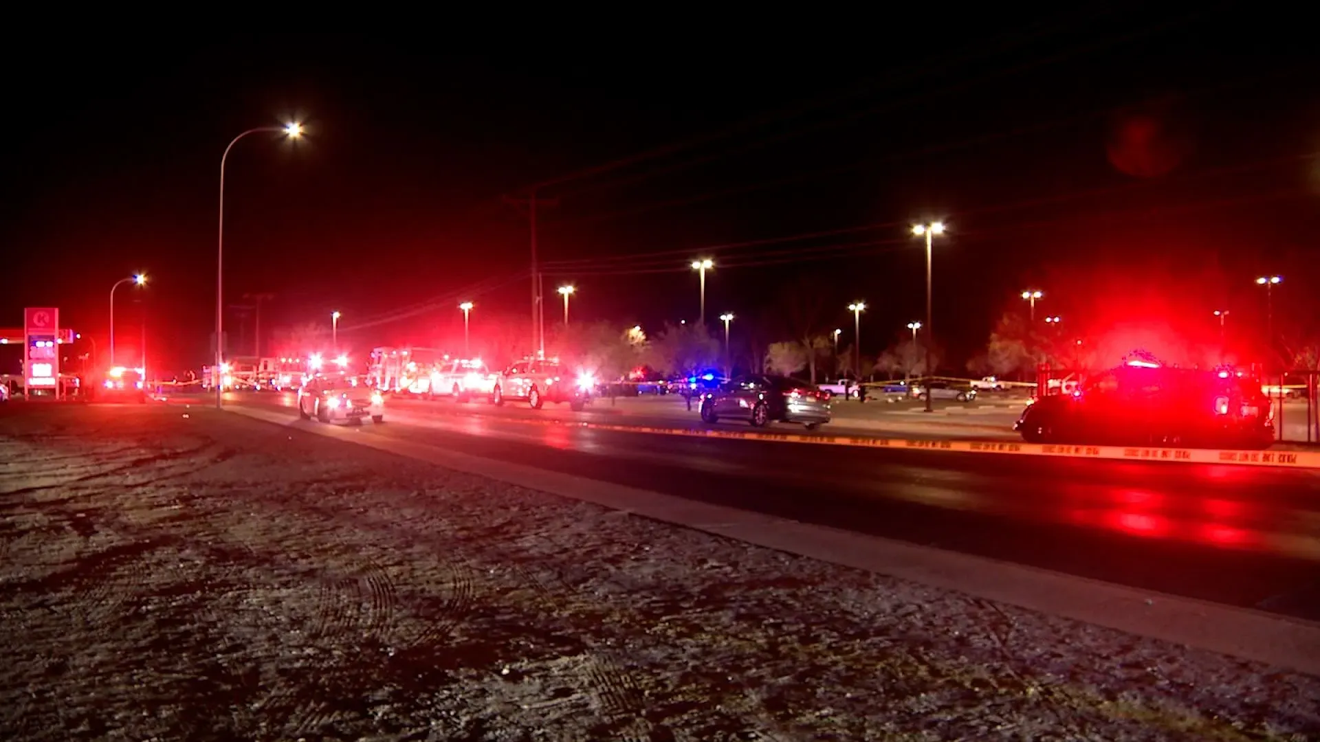 موقع إطلاق نار جماعي في لاس كروسيس، يظهر سيارات الشرطة والإسعاف والأضواء اللامعة، مع وجود شريط تحذيري حول المنطقة.