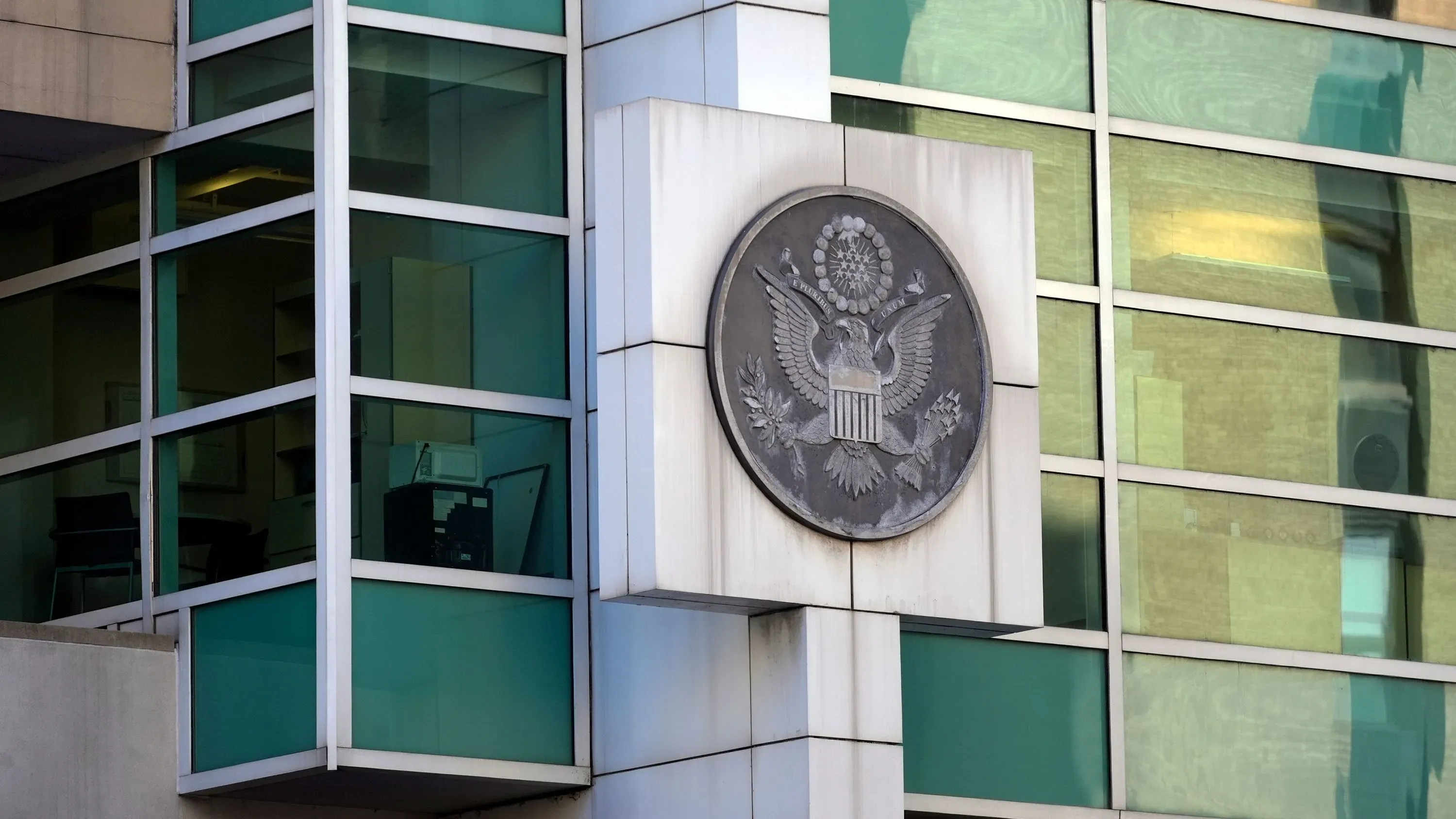 شعار الحكومة الأمريكية على واجهة مبنى زجاجي، يرمز إلى قضايا الهجرة والحقوق المدنية المتعلقة بترحيل الأطفال.