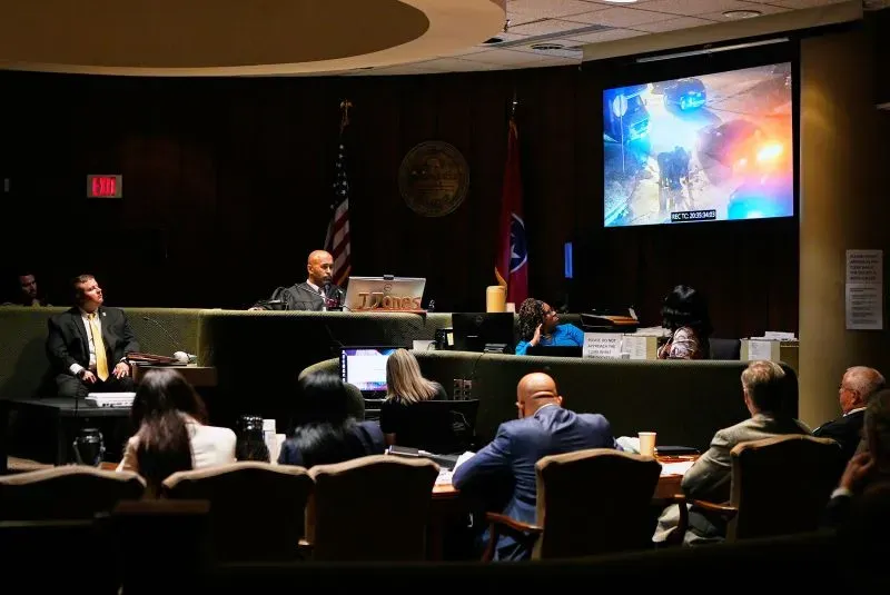 عرض في قاعة المحكمة مشهد من كاميرا المراقبة يظهر الضباط أثناء محاكمة تتعلق بوفاة تاير نيكولز، مع وجود محامين وأعضاء هيئة المحلفين.