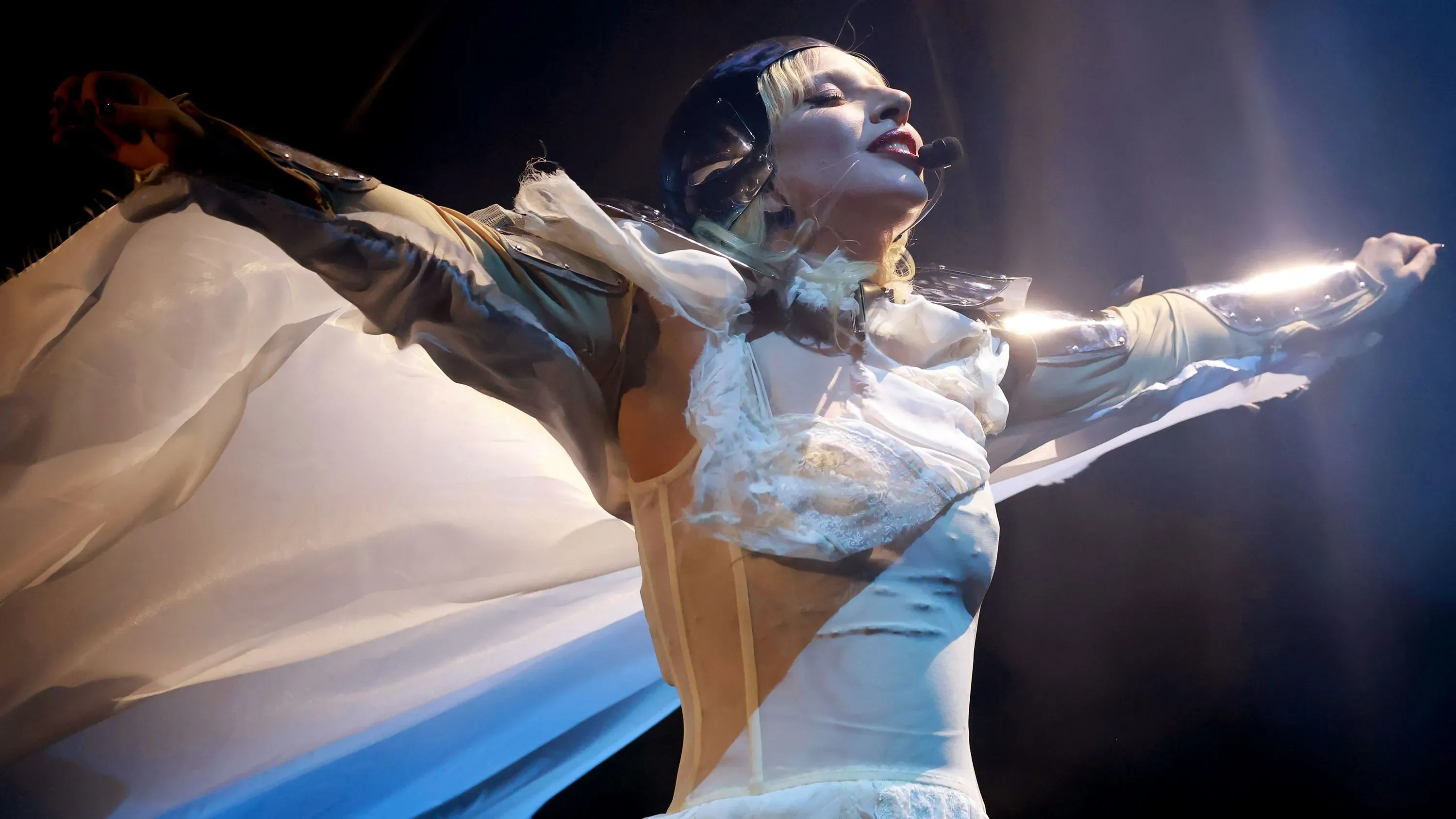 ليدي غاغا تؤدي على المسرح في مهرجان كوتشيلا، مرتدية زيًا قوطياً مع تأثيرات ضوئية مبهرة، بينما تتفاعل مع الجمهور.