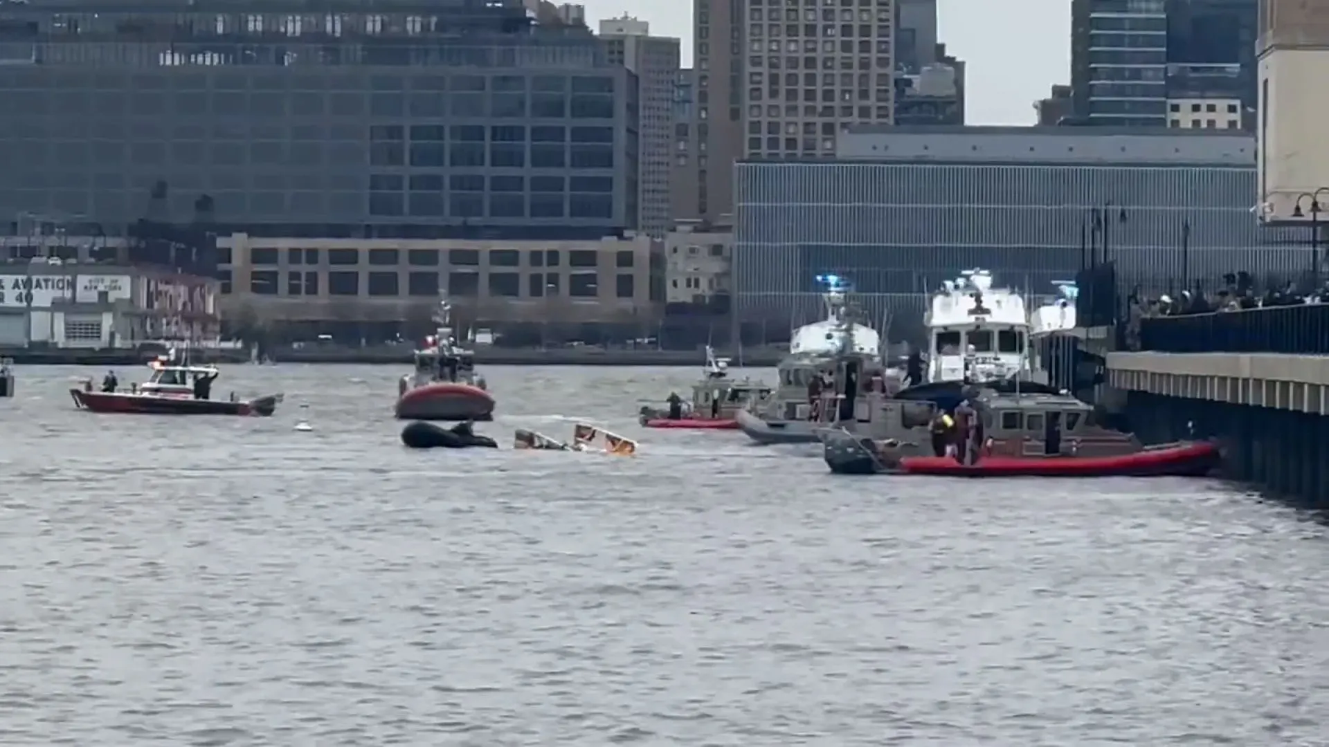 حادث تحطم مروحية في نهر هدسون، مع وجود قوارب إنقاذ للبحث عن المفقودين، والخلفية تظهر المباني في نيويورك.