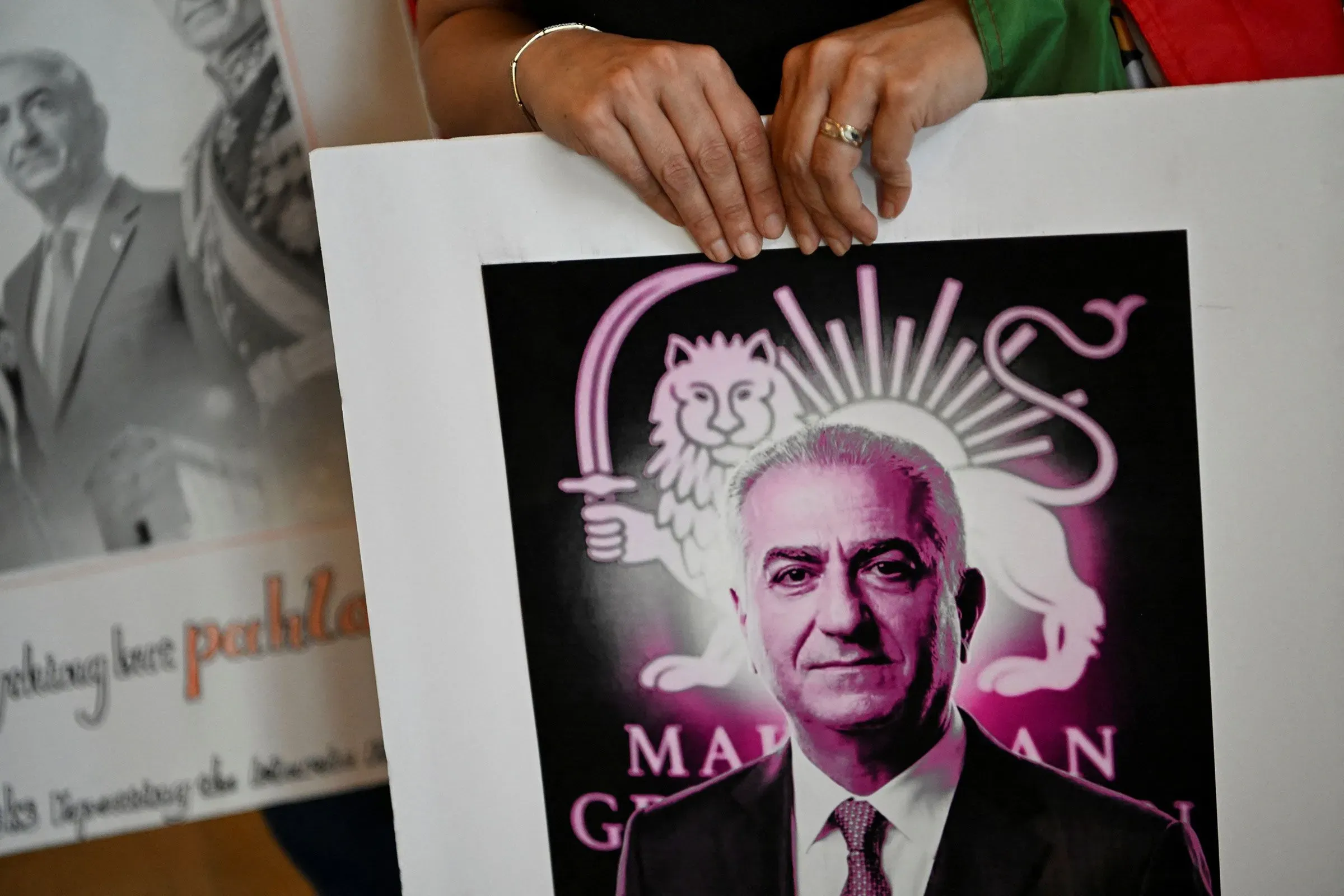 شخص يحمل لافتة تحمل صورة رضا بهلوي، زعيم المعارضة الإيرانية، خلال مؤتمر العمل السياسي المحافظ في تكساس.