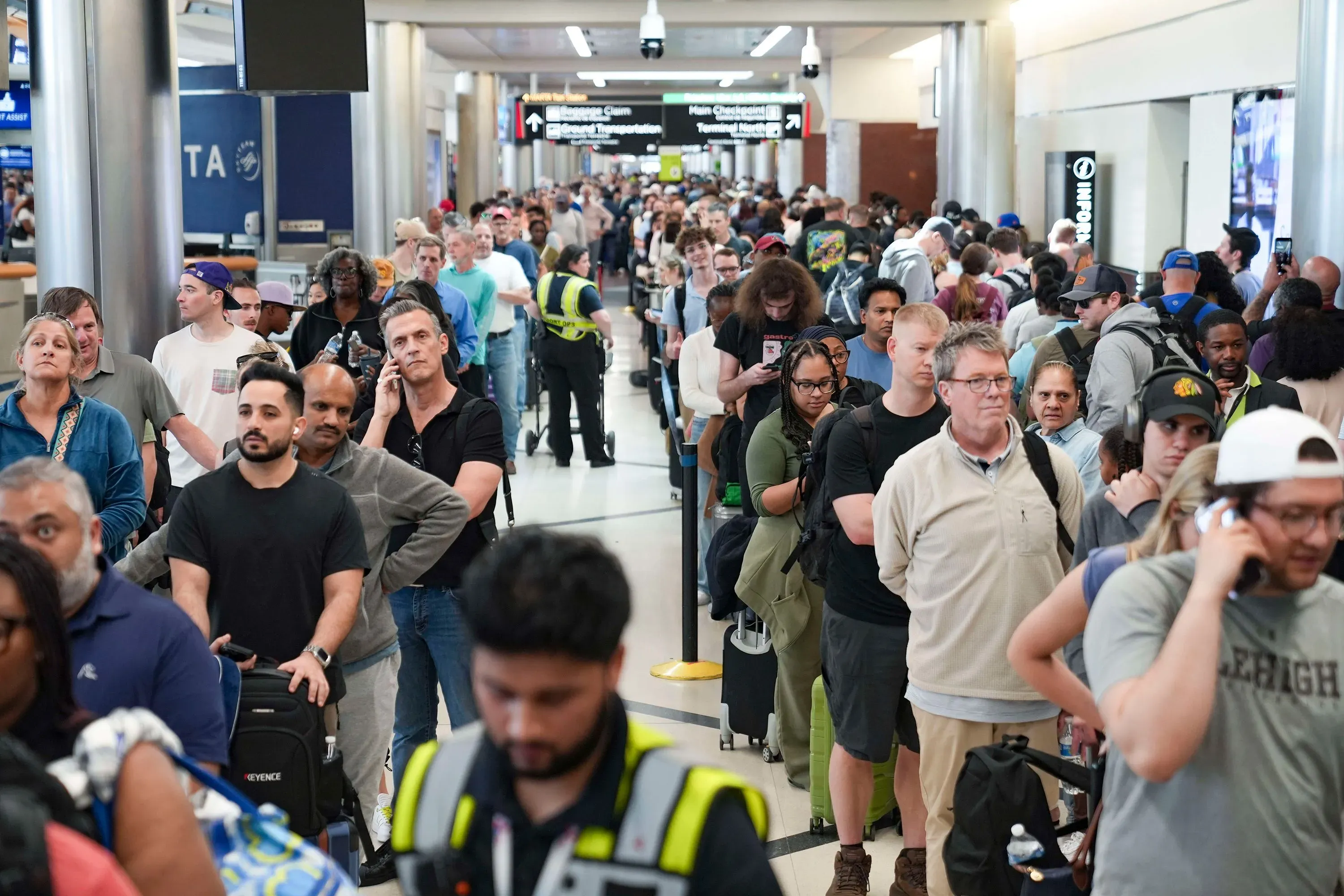 طوابير طويلة من المسافرين في مطار مزدحم، تعكس تأثير الإغلاق الجزئي للحكومة على إدارة أمن المواصلات.