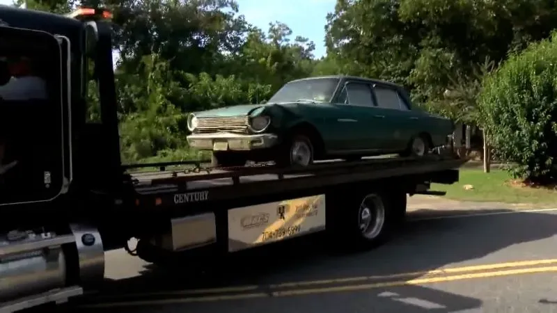 سيارة قديمة خضراء تُحمَل على شاحنة سحب، بالقرب من موقع اختفاء الطفلة آشا دجري في نورث كارولينا، حيث تُجري السلطات تحقيقات جديدة.