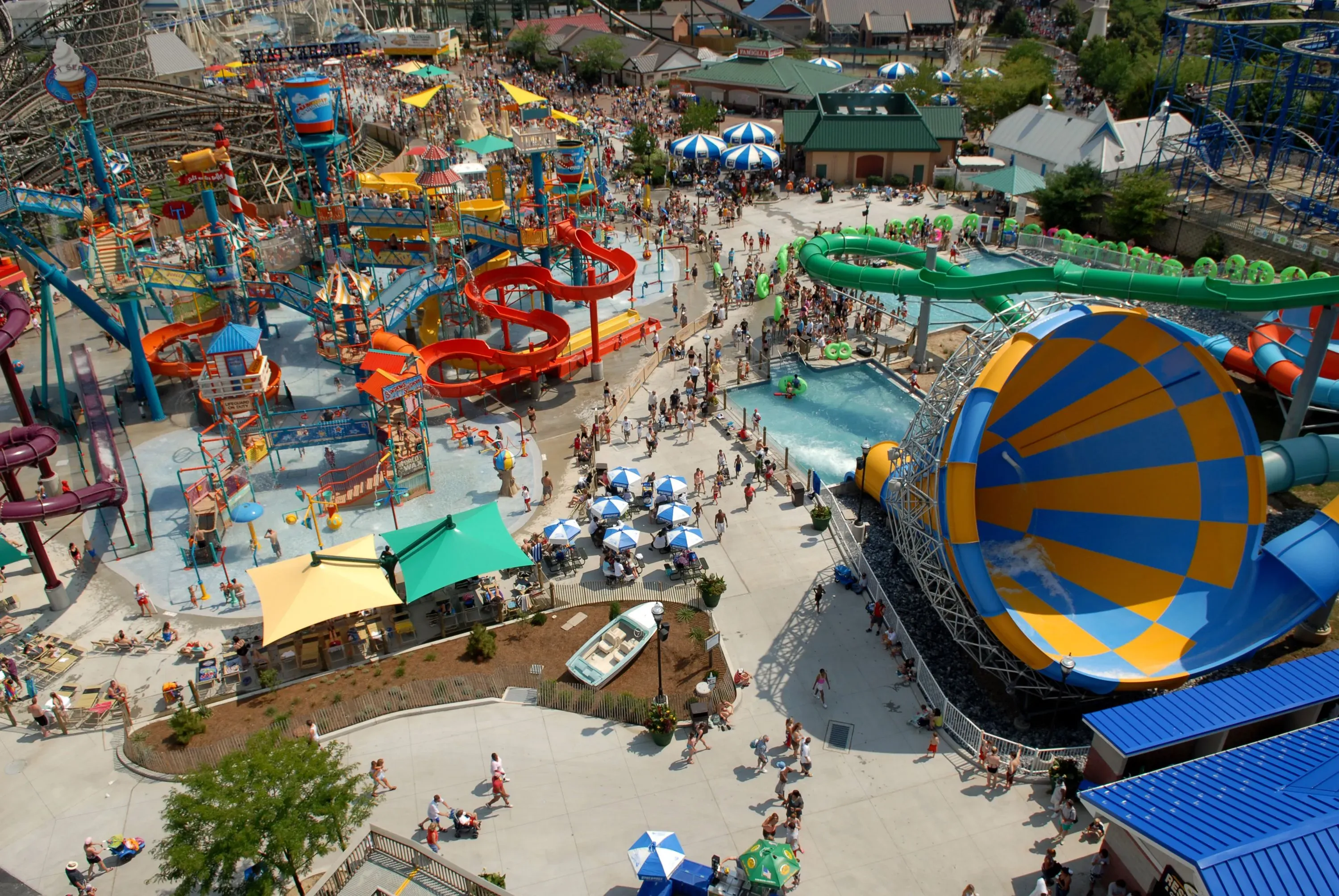 مشهد من متنزه هيرشي بارك المائي يظهر الزوار يستمتعون بالألعاب المائية، بما في ذلك منزلقات وحوض سباحة، وسط أجواء حيوية.