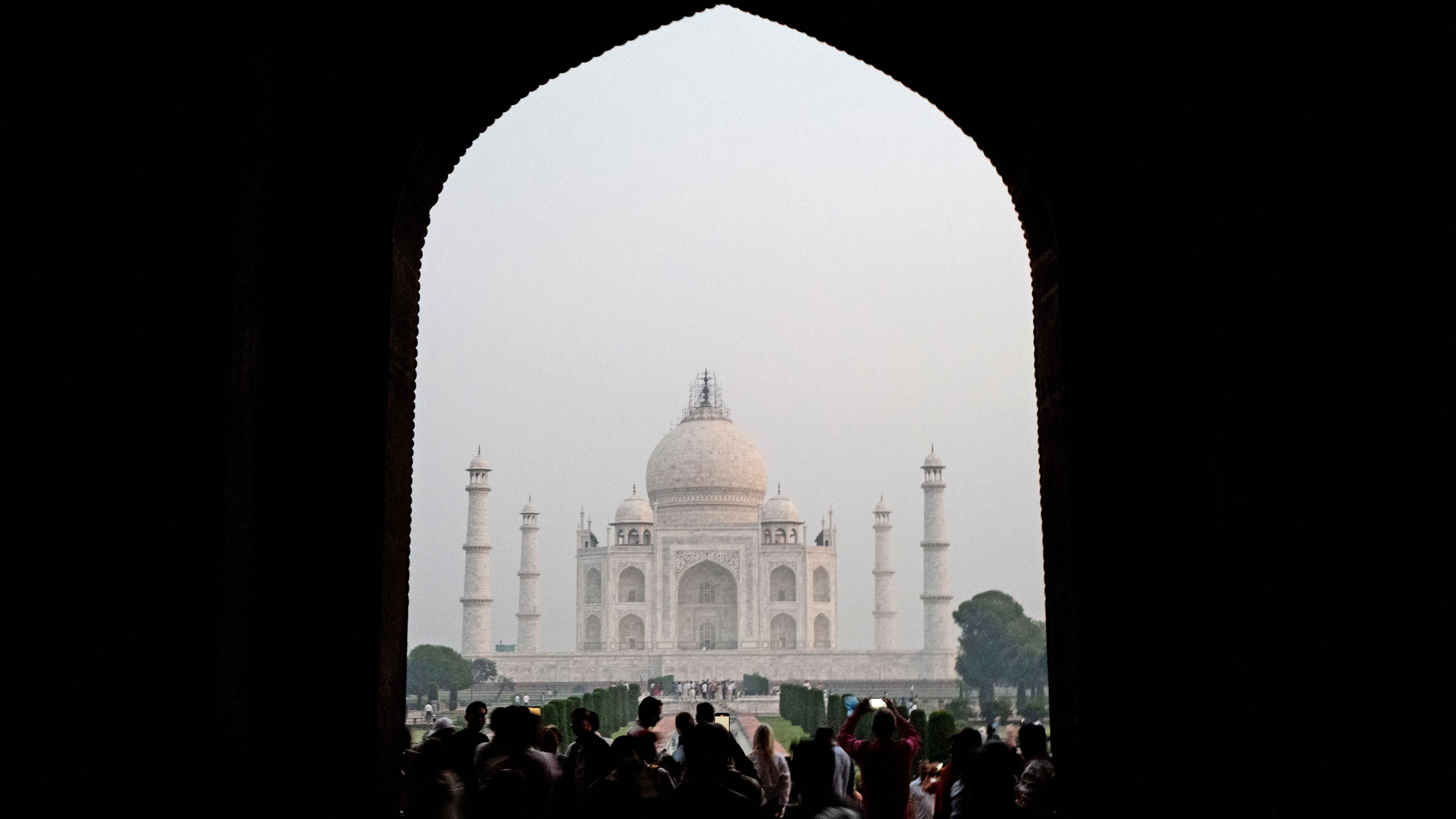 تاج محل، المعلم الشهير، يظهر من خلال قوس مظلم، محاط بالزوار. يعكس الفيلم "قصة تاج" جدلاً حول أصله وتاريخه.