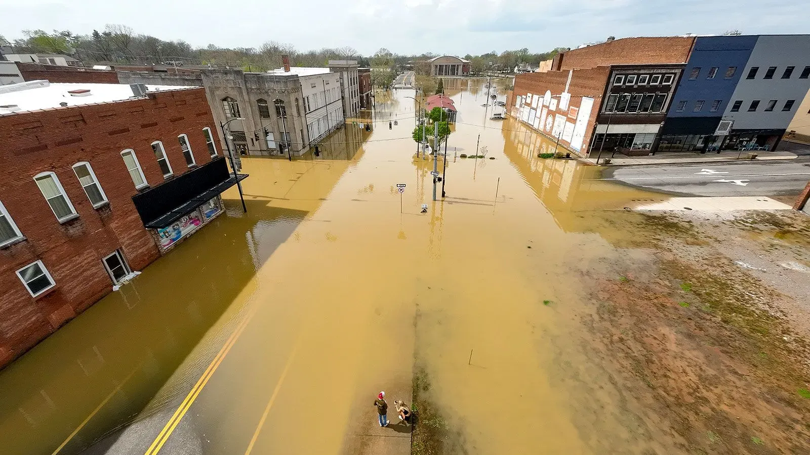 فيضانات عارمة تغمر الشوارع في ولاية كنتاكي، مع ظهور المباني جزئيًا تحت المياه، مما يعكس تأثير العواصف القوية.
