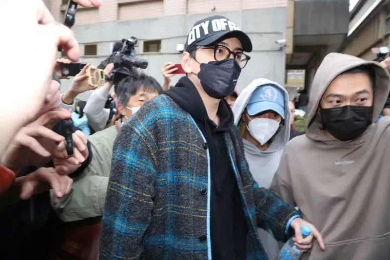 مشهد لممثل يواجه حشودًا من المعجبين والصحفيين بعد اتهامه بالتهرب من التجنيد في تايوان، وسط أجواء من التوتر والجدل.