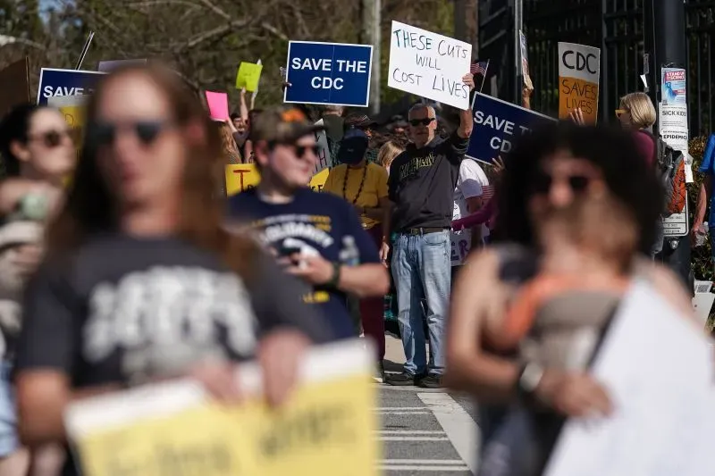 محتجون يحملون لافتات تدعو لحماية مركز السيطرة على الأمراض، مع التركيز على أهمية الحفاظ على البرامج الصحية في مواجهة التخفيضات.