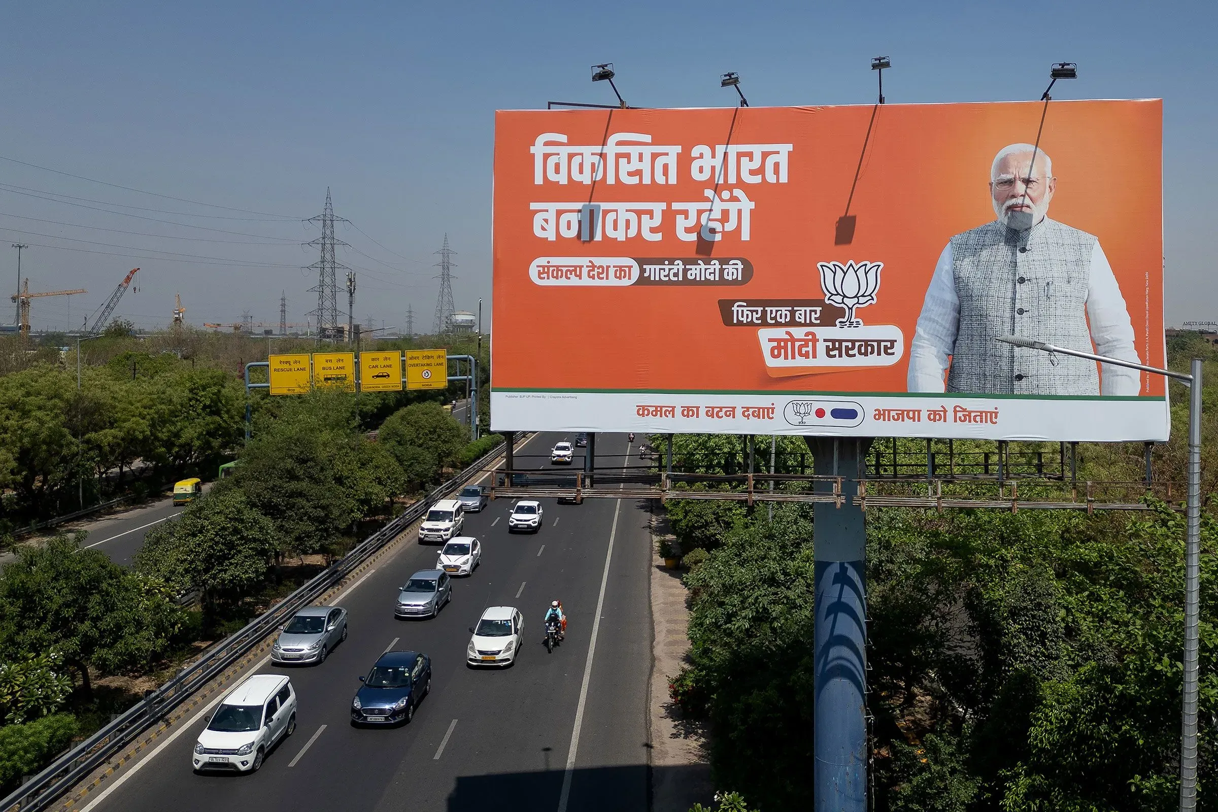 لافتة إعلانية كبيرة في الهند تدعم حزب بهاراتيا جاناتا، تظهر صورة لرئيس الوزراء مودي مع نص تشجيعي حول التنمية الوطنية.