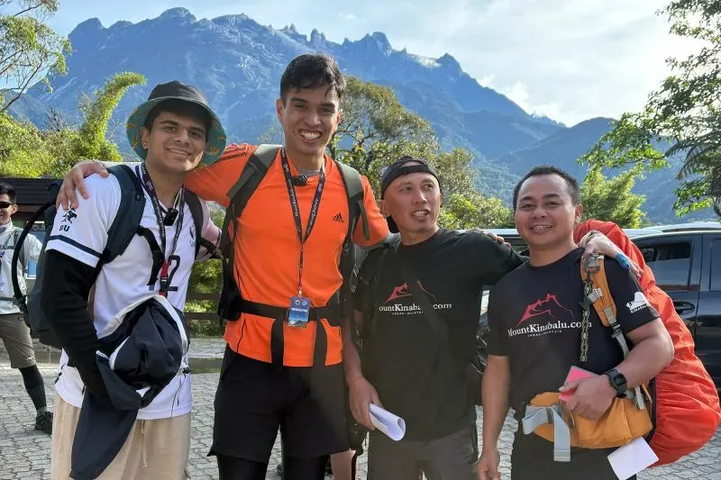 اجتمع أربعة رجال مبتسمين في قاعدة جبل كينابالو، يرتدون ملابس رياضية، مع خلفية جبلية رائعة، في ذكرى الذكرى العاشرة للزلزال.