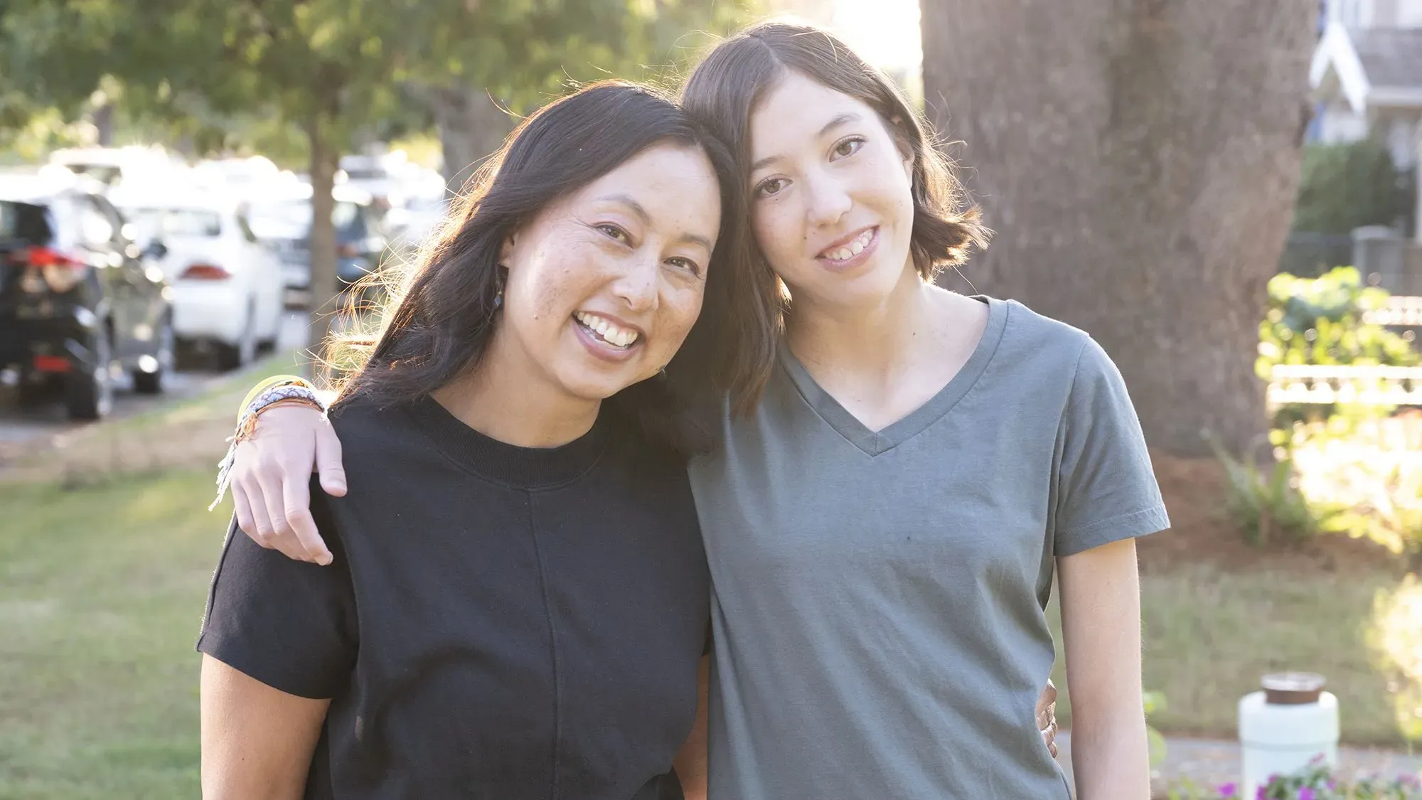 أديسون ماك آرثر، التي خضعت لزراعة قلب، تحتفل بعيد ميلادها الرابع عشر مع والدتها إيلين يونغ في حديقة، مع سيارات خلفهما.