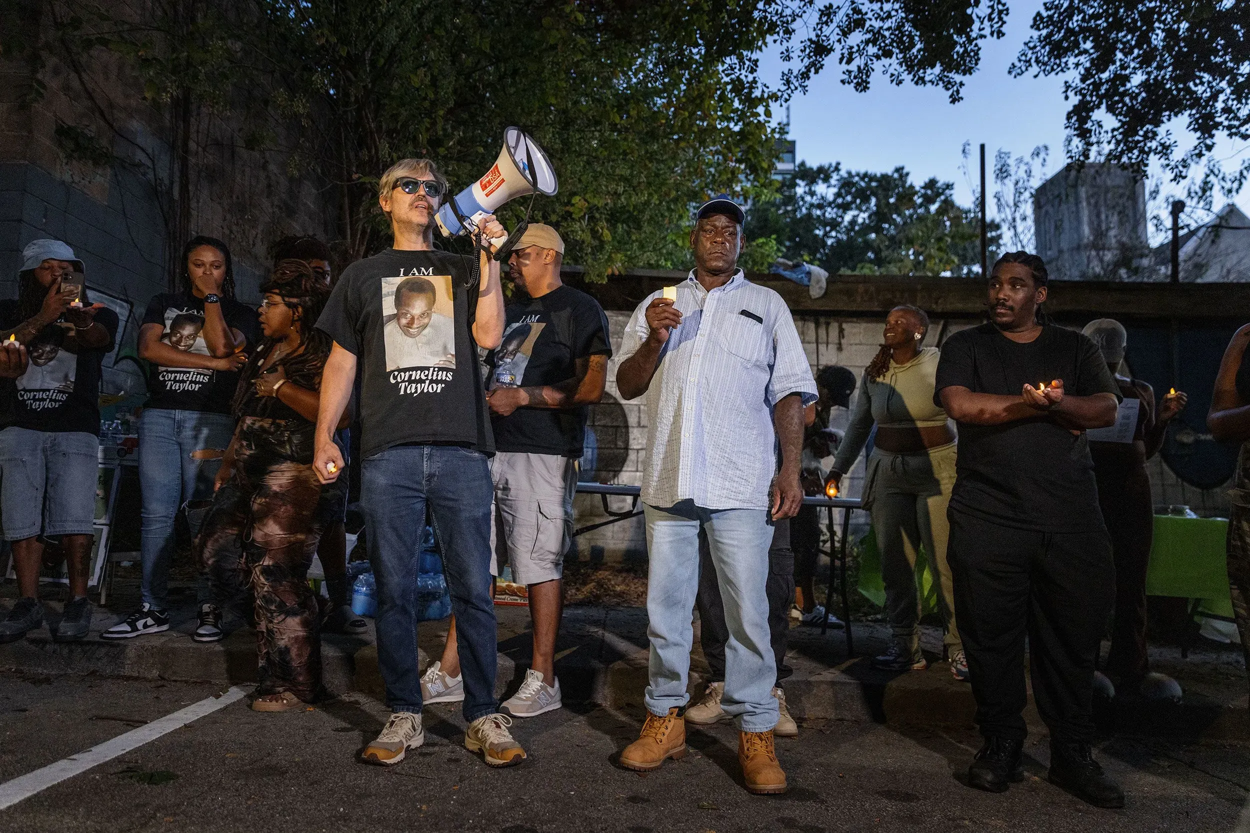 تجمع حشد من الأشخاص في أتلانتا لإحياء ذكرى كورنيليوس تايلور، حيث يحمل أحدهم مكبر صوت ويعبر عن الحزن على وفاته.