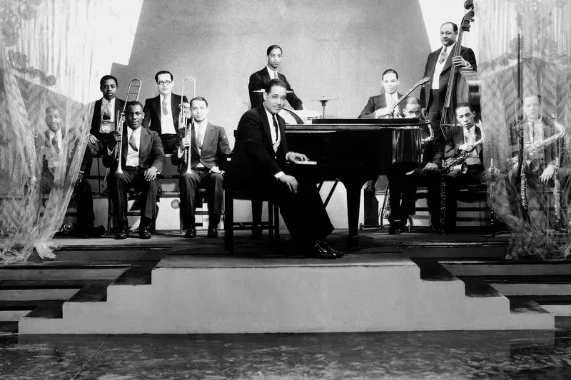 فرقة موسيقية شهيرة من عصر النهضة في هارلم، تضم عازف بيانو وموسيقيين يرتدون بدلات أنيقة، تعكس تأثير الثقافة السوداء في الموضة.