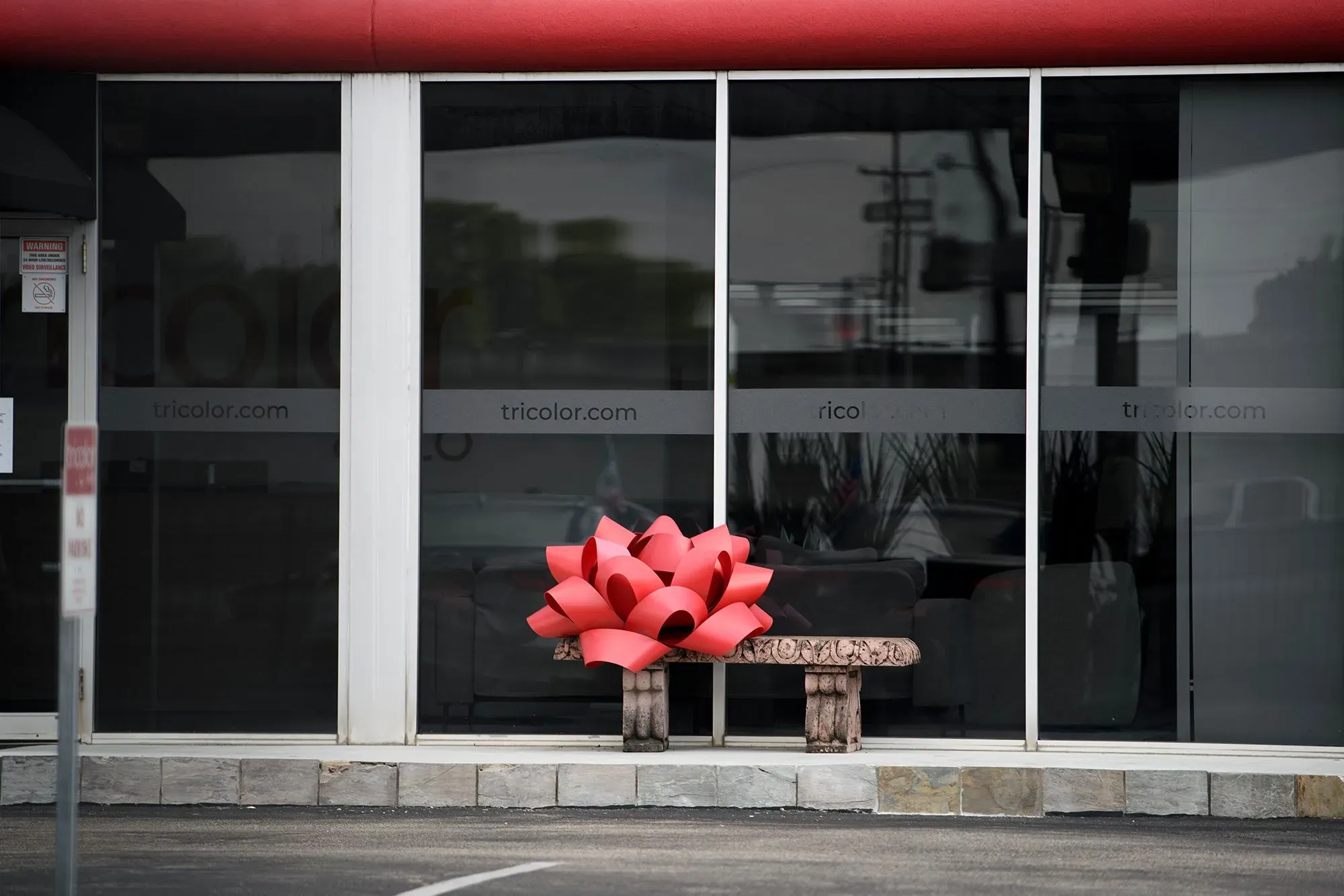 واجهة متجر Tricolor مغلقة، مع وجود زينة حمراء كبيرة على مقعد أمامي، مما يعكس توقف الشركة عن العمل.