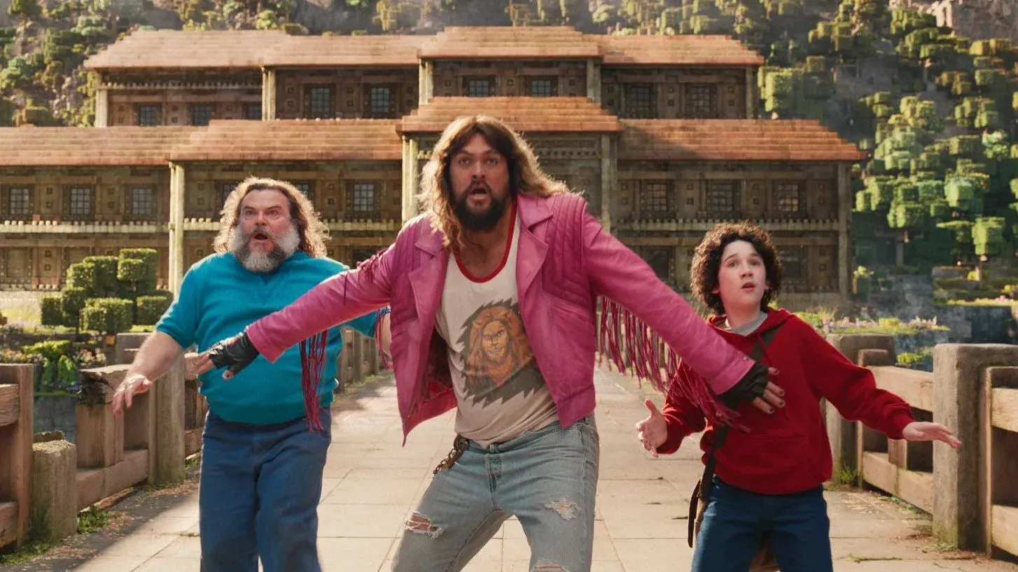 شخصيات من فيلم "ماين كرافت" تتفاعل في مشهد حيوي، مع خلفية مناظر طبيعية مستوحاة من اللعبة، تعكس نجاح الفيلم في شباك التذاكر.