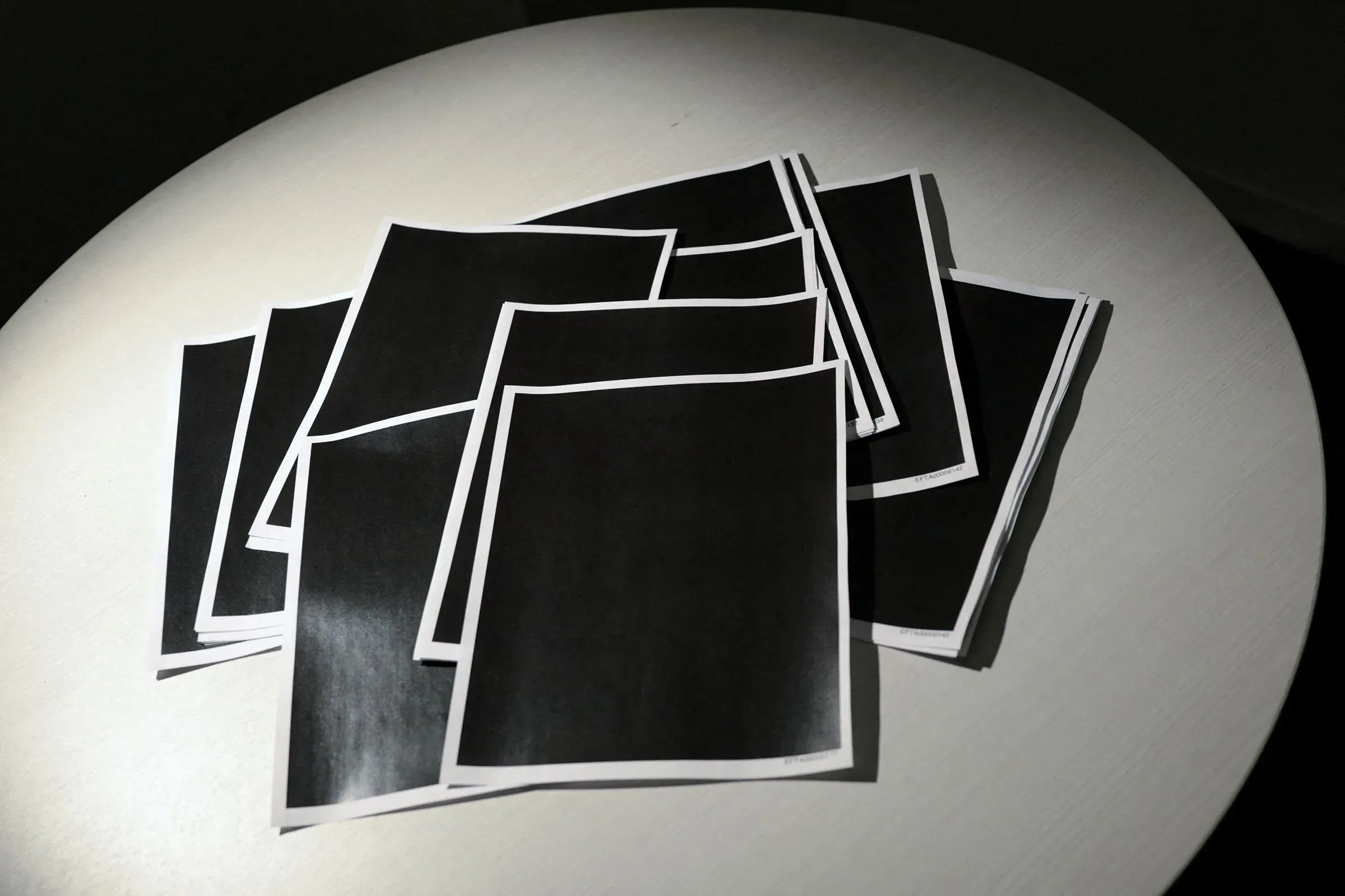 مجموعة من الأوراق المطبوعة باللون الأسود موضوعة على طاولة، تعكس حالة الغموض حول المعلومات المتعلقة بقضية جيفري إبستين.