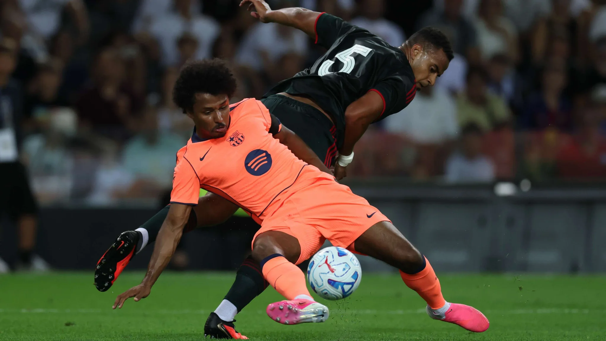 لاعب من برشلونة يرتدي زي برتقالي يتحدى لاعب الأهلي في مباراة ودية ضمن كأس جوان جامبر على ملعب كامب نو.