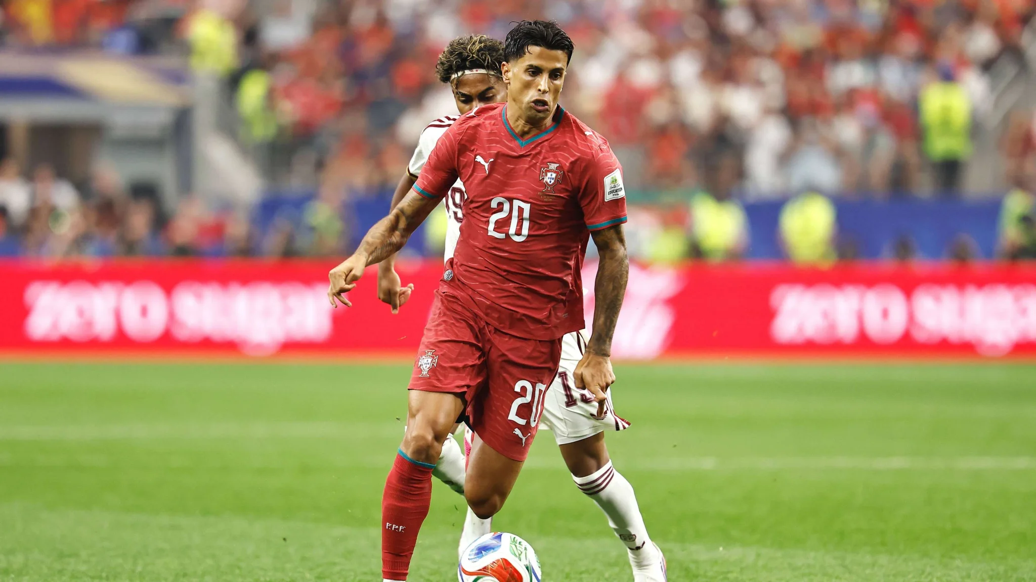 جواو كانسيلو لاعب كرة قدم برتغالي يرتدي زي منتخب بلاده، يركض بالكرة خلال مباراة، مع توقع عودته إلى برشلونة لتعزيز الدفاع.