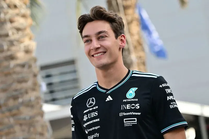 سائق مرسيدس جورج راسل مبتسم خلال مؤتمر صحفي قبل سباق جائزة البحرين الكبرى، حيث يتحدث عن تحديات الالتزام بالمواعيد في سباقات الفورمولا 1.