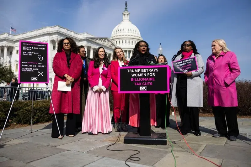 مجموعة من النساء الديمقراطيات يرتدين الملابس الوردية ويعبرن عن احتجاجهن أمام مبنى الكابيتول، مع لافتات تنتقد سياسات ترامب.