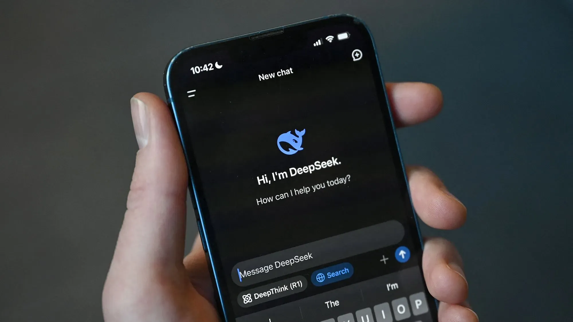 واجهة تطبيق DeepSeek على الهاتف، تعرض رسالة ترحيبية مع شعار الشركة. تشير الصورة إلى التطور في الذكاء الاصطناعي وتأثيره على السوق.