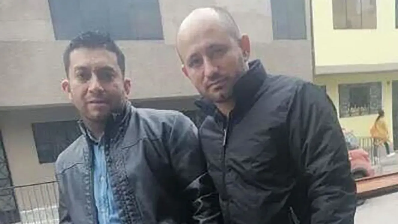 صورة لرجلين، أحدهما في زي رسمي والآخر بملابس غير رسمية، يقفان معًا في منطقة حضرية. تعكس الصورة الروابط الأسرية والدعم الإنساني في سياق التبرع بالأعضاء.