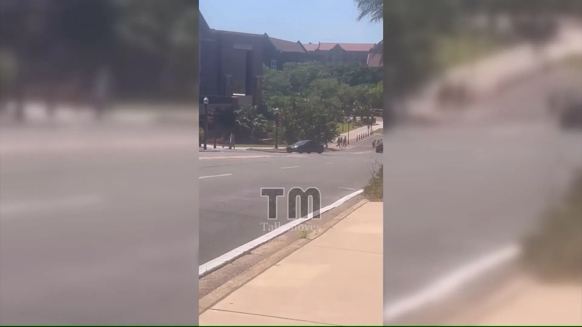 طلاب يركضون في حالة من الذعر بعد سماع إطلاق نار في حرم جامعة ولاية فلوريدا، مع وجود مركبات الشرطة في الخلفية.