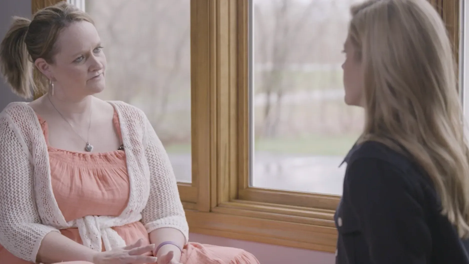 تظهر كريستال كويغلي، امرأة في مرحلة التعافي من الإدمان، تتحدث مع صحفية في غرفة مضاءة بشكل طبيعي، تعكس تحديات الإدمان والتعافي.