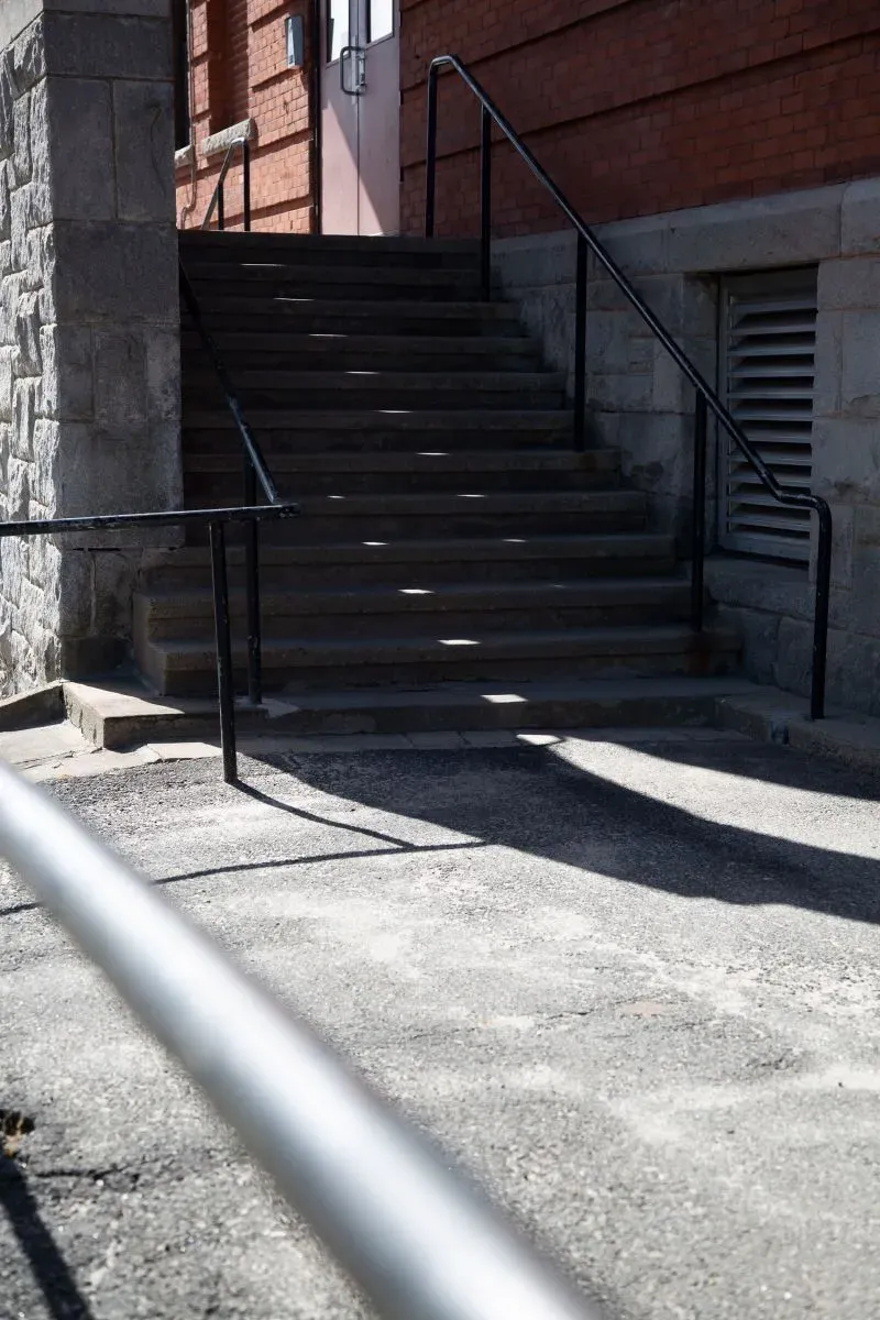 مدخل مدرسة بارنارد الابتدائية، مع درج صاعد ودرابزين، يشير إلى مكان شهد ذكريات مأساوية تتعلق بحالة احتجاز وسوء معاملة.