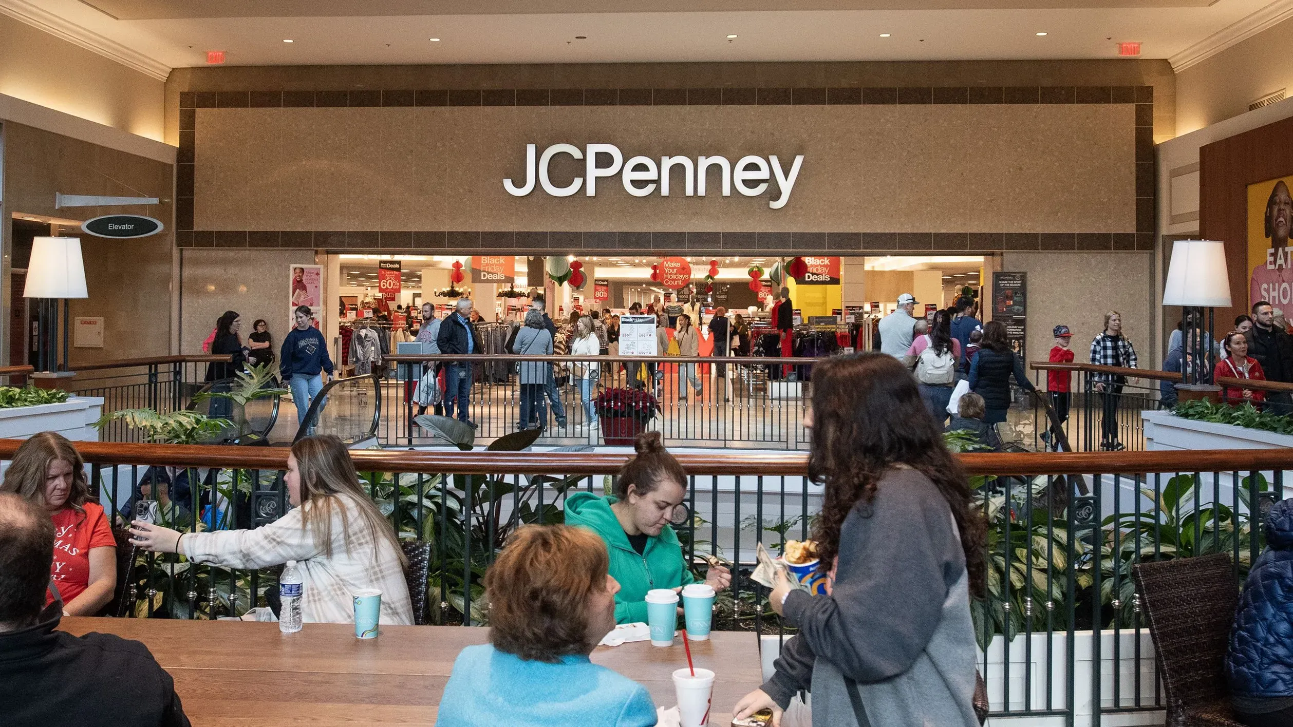 واجهة متجر JCPenney في مركز تسوق مزدحم، مع زبائن يتجولون ويستعرضون الملابس، مما يعكس نشاط العلامة التجارية في فترة الإنعاش.