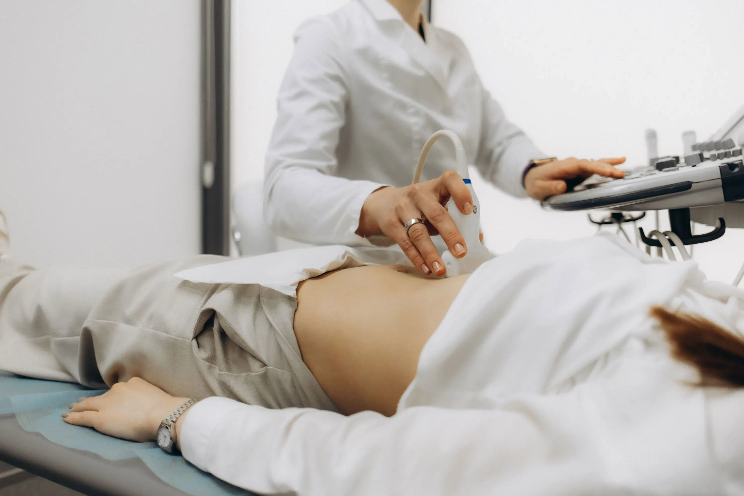 طبيبة تستخدم جهاز السونار لفحص امرأة حامل في عيادة طبية، مما يعكس أهمية الرعاية السابقة للولادة في تحسين صحة الأمهات.