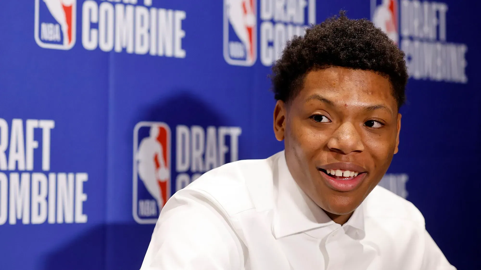 بيلي، لاعب كرة سلة شاب، يتحدث خلال مؤتمر صحفي بعد اختياره في مسودة الدوري الأمريكي للمحترفين، مع خلفية تحمل شعار "درافت كومباين".
