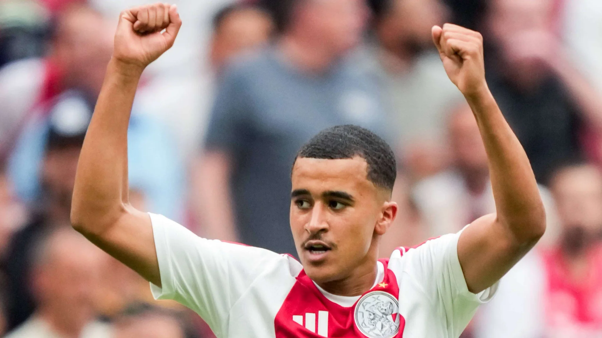 عبدالله وازان لاعب وسط أياكس يحتفل برفع يديه خلال مباراة، مع تركيزه على تمثيل المغرب دولياً رغم تمثيله السابق لهولندا في فئات الشباب.