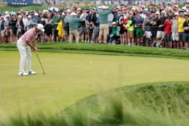 آدم سكوت يسدد الكرة على أرضية الملعب في بطولة الولايات المتحدة المفتوحة، مع جمهور كبير يشاهد خلفه.