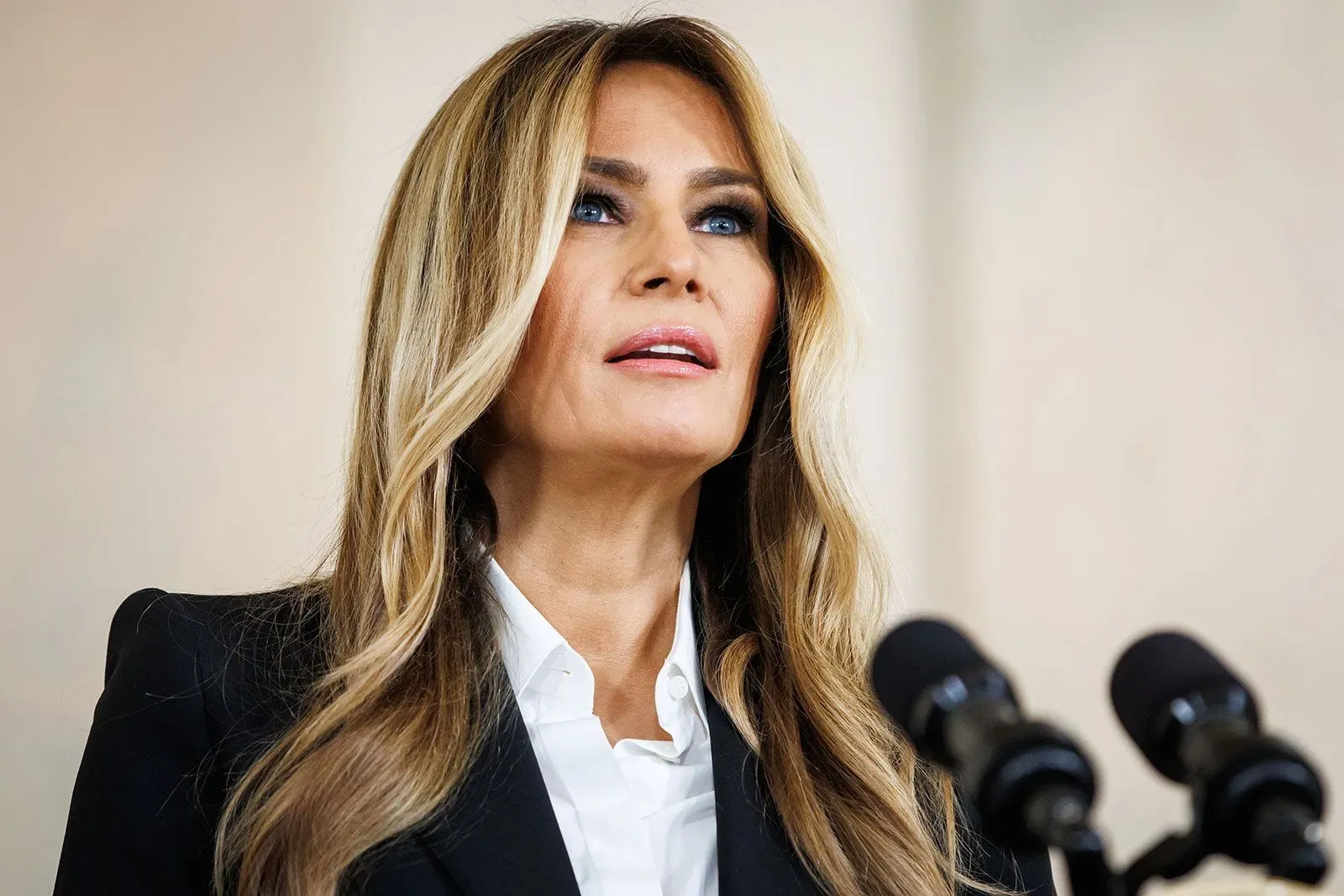 ميلانيا ترامب تتحدث في مؤتمر صحفي، مع التركيز على قضية إعادة الأطفال الأوكرانيين، تعبيرات وجهها تعكس الجدية والاهتمام.