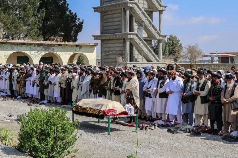 مجموعة من الأشخاص يؤدون الصلاة في جنازة، مع وجود جثة مغطاة على منصة، في سياق أحداث العنف الأخيرة بين أفغانستان وباكستان.