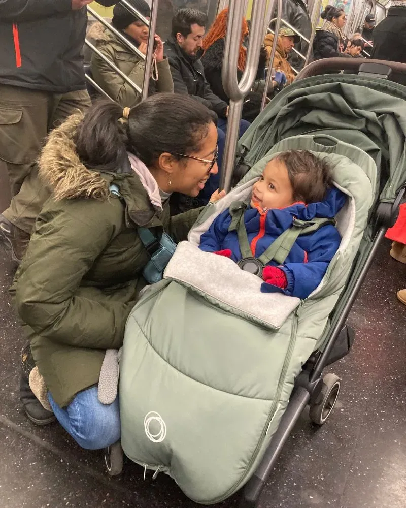 امرأة تتحدث مع طفلها في عربة قطار تحت الأرض، حيث يظهر الطفل في عربة أطفال مرتديًا ملابس دافئة، مما يعكس لحظة حميمية بينهما.