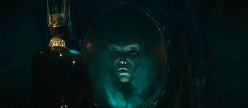 مشهد من فيلم "بياض الثلج" الجديد، يظهر الملكة الشريرة أمام مرآة سحرية تعكس وجهها بطريقة غامضة، مما يعكس التوتر في القصة.