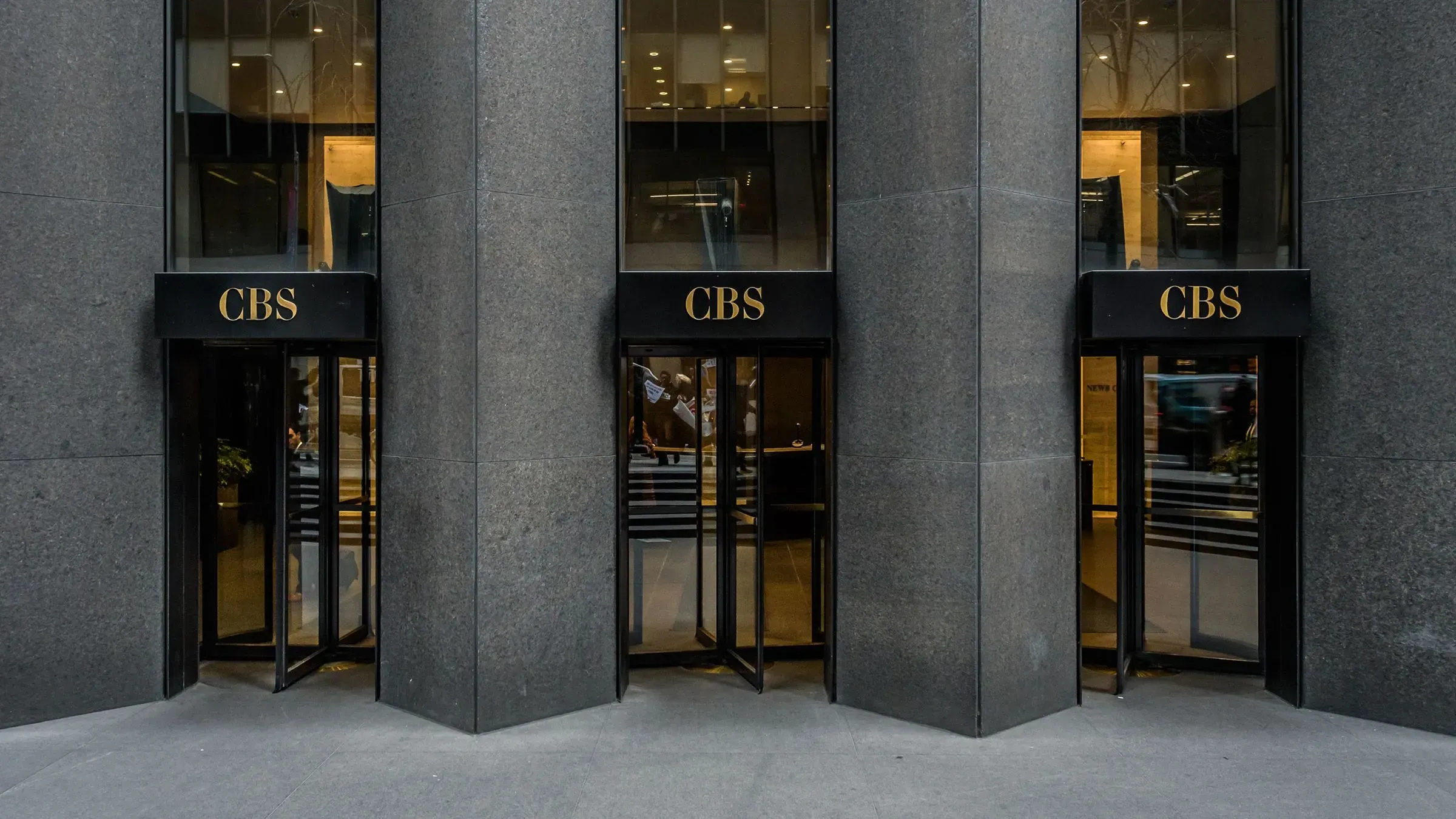 مدخل مبنى شبكة سي بي إس نيوز، مع لافتات تحمل اسم الشبكة، يعكس التوترات المحيطة بتسوية باراماونت مع ترامب.