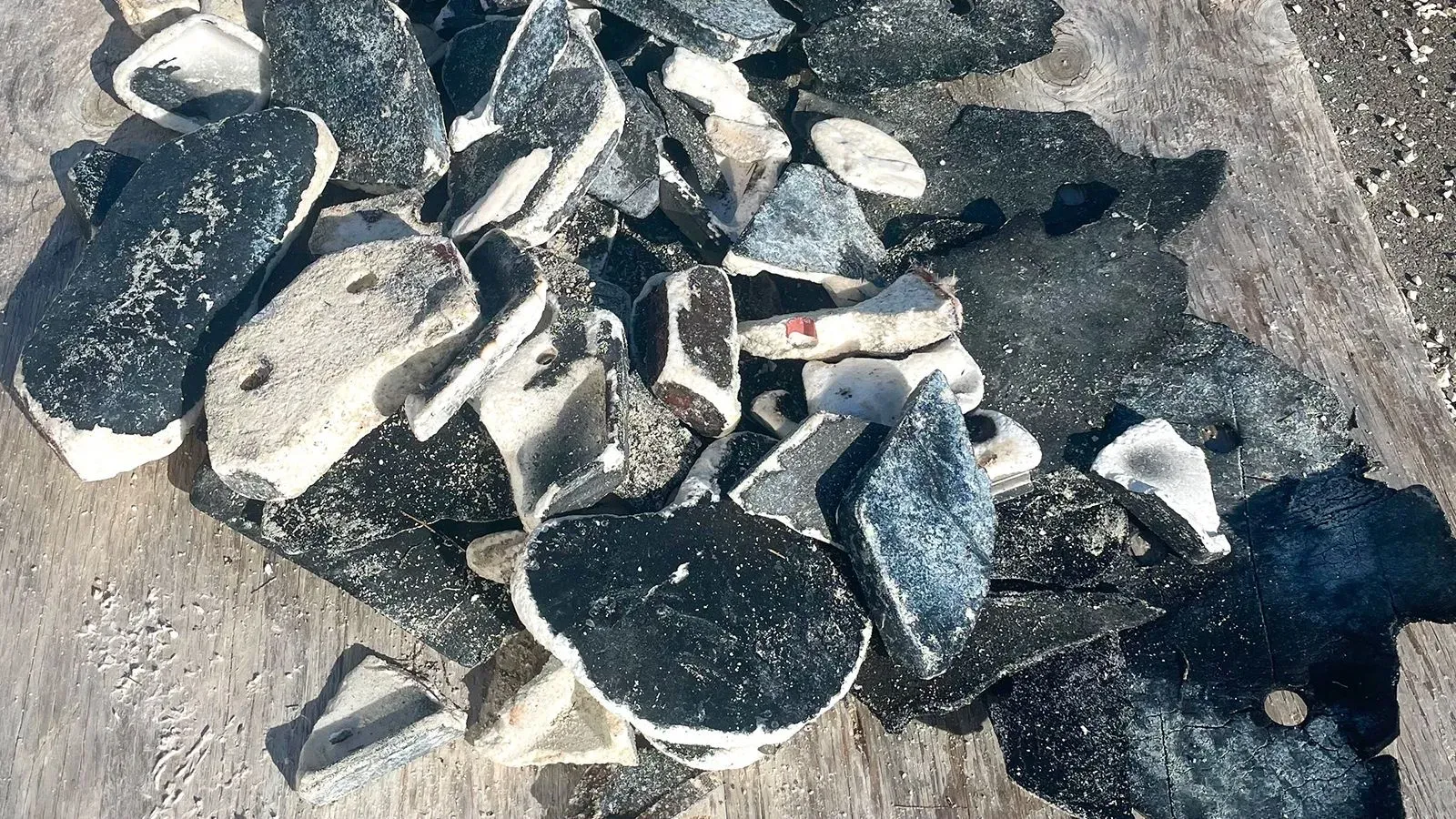 قطع من الحطام الفضائي، تتضمن أجزاء مكسورة من المركبة، متناثرة على سطح خشبي، تعكس آثار الانفجار الذي حدث فوق المحيط الأطلسي.