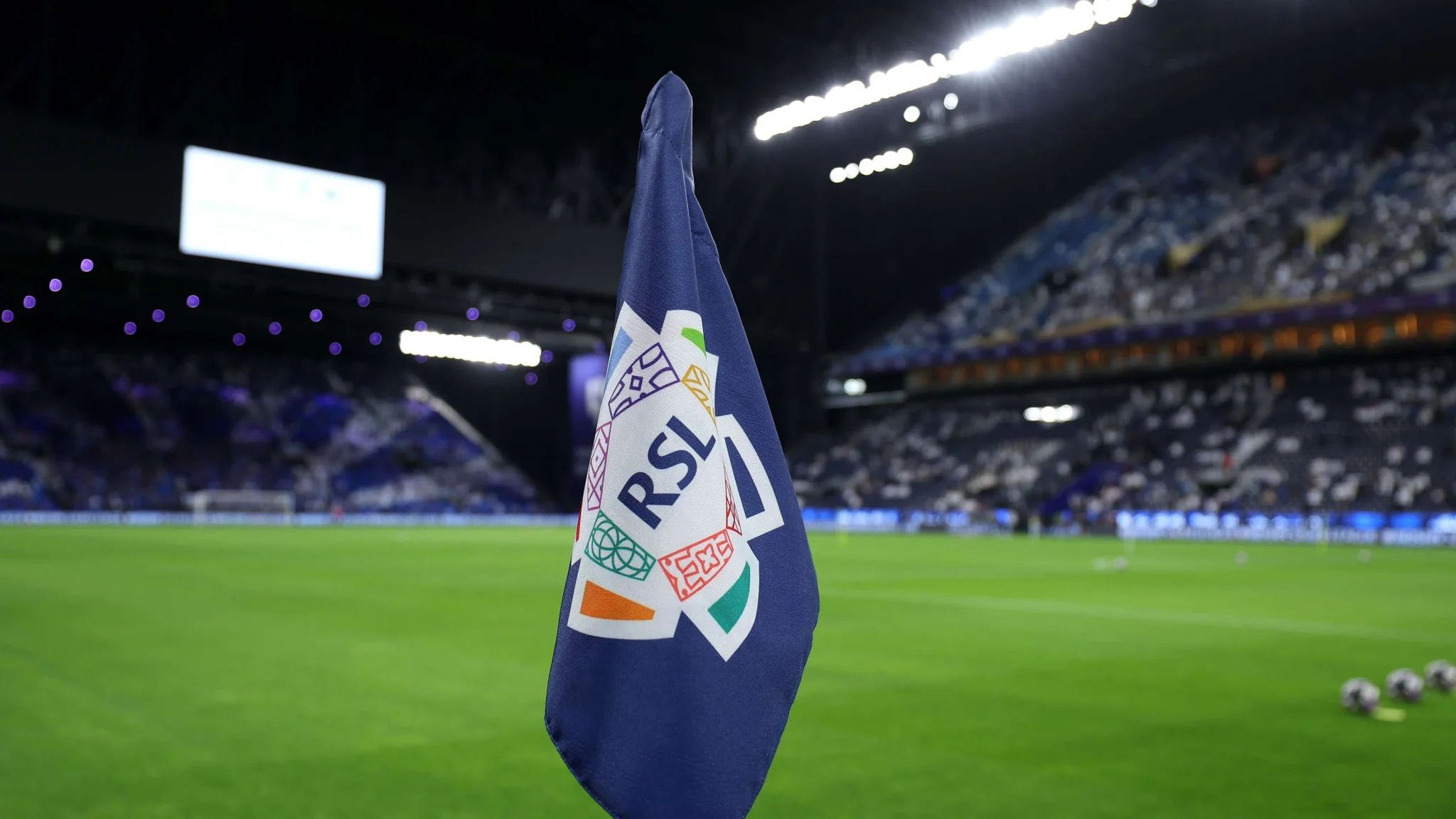 علم دوري روشن السعودي يرفرف في ملعب كرة قدم مضاء استعدادًا لمباريات دوري المحترفين السعودي.
