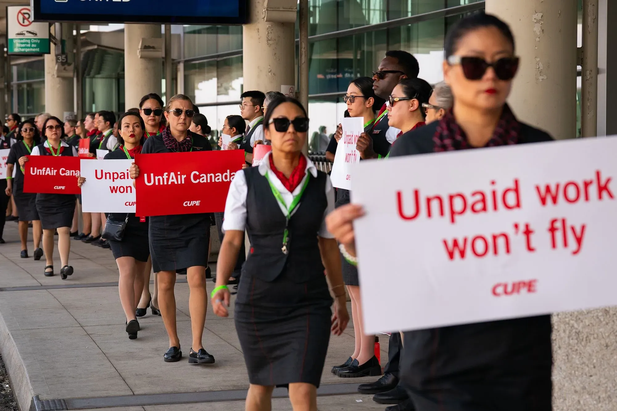 مضيفات الخطوط الجوية الكندية يتظاهرن حاملات لافتات تطالب بتحسين الأجور وظروف العمل، وسط أزمة إضراب محتملة.