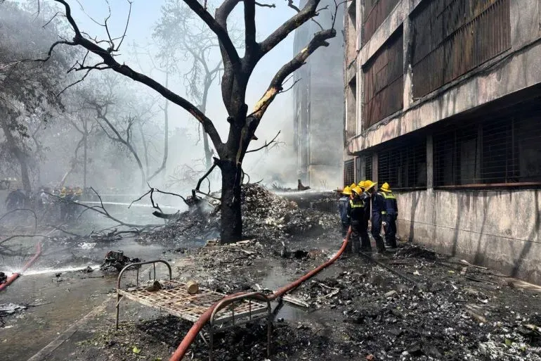 موقع تحطم طائرة الخطوط الجوية الهندية في ميغاني ناغار، مع رجال الإطفاء يعملون على إخماد النيران وسط الدخان والأنقاض.