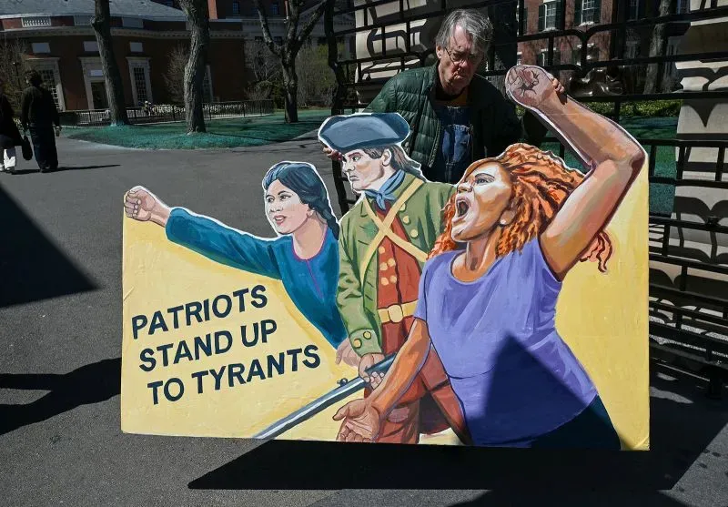 لافتة ملونة تحمل عبارة "الوطنون يقفون ضد الطغاة"، مع رسومات لثلاث شخصيات تاريخية، تعكس روح المقاومة.