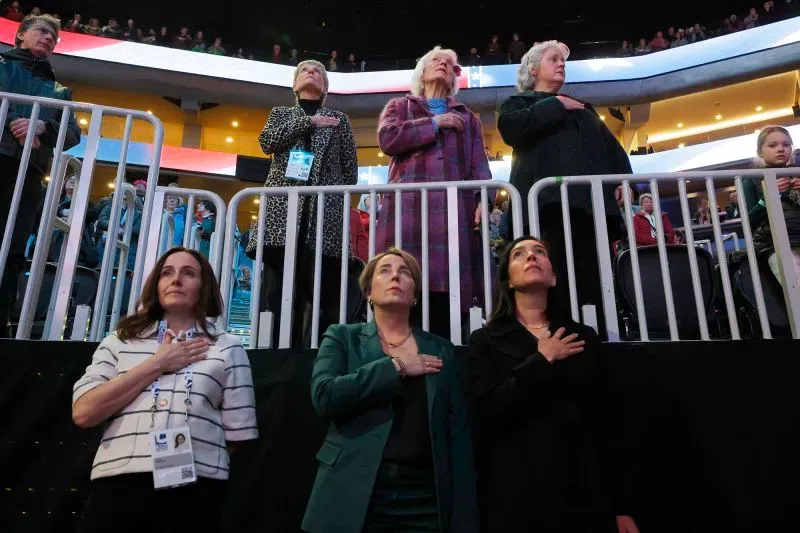 مجموعة من النساء يقفن في صمت مع وضع أيديهن على قلوبهن، خلال مراسم تأبين في بطولة العالم للتزلج على الجليد في بوسطن.